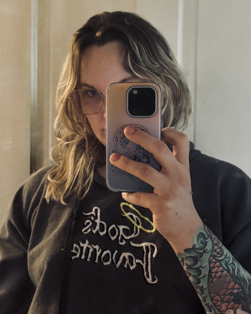 Ryan taking a selfie in the mirror wearing a gray hoodie with the phrase God's Favorite embroidered on it.