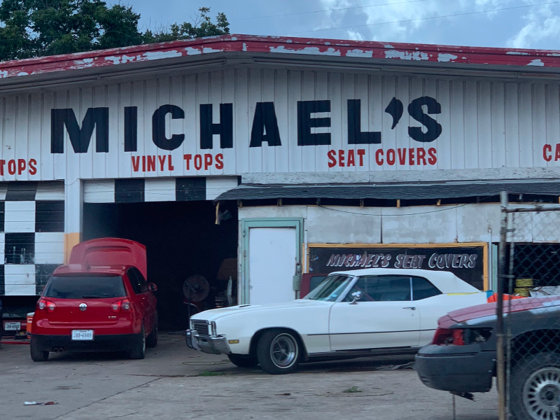 A photo of a body shop called Michael's. The sign is black block letters.
